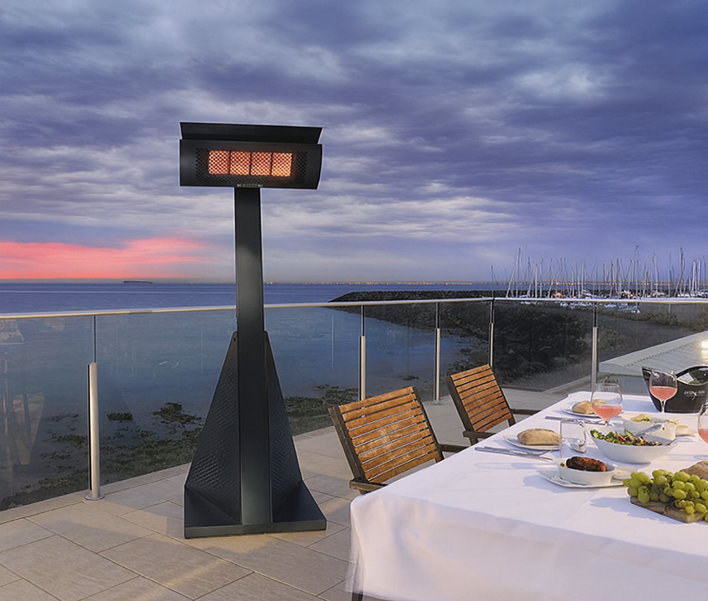 Outdoor patio heater on a deck with a table set for dinner by the water.